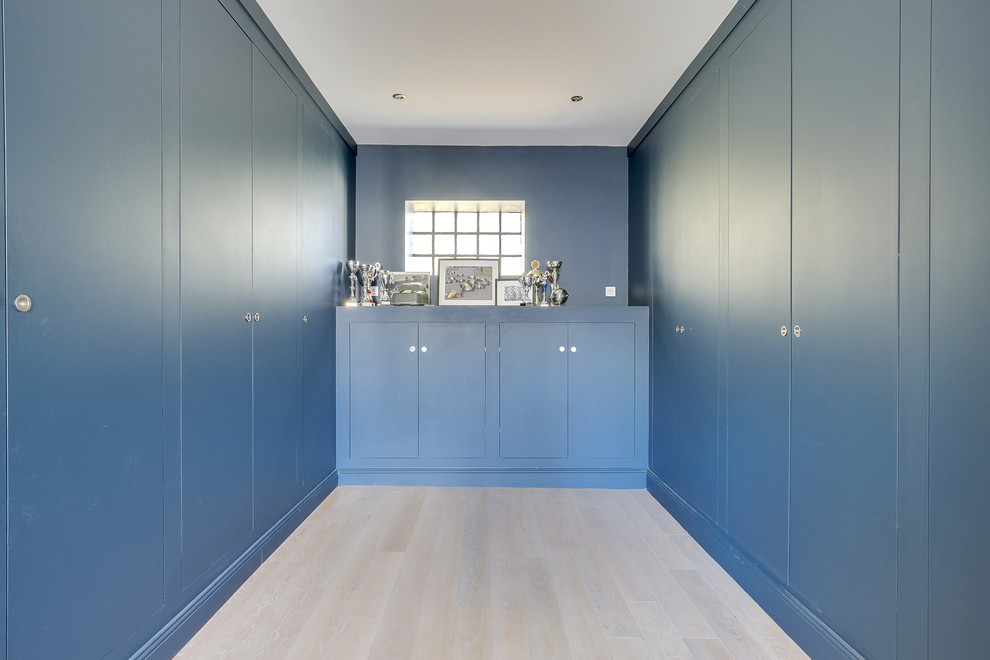 Foto de despacho minimalista de tamaño medio sin chimenea con paredes azules, suelo de madera clara, escritorio independiente y suelo beige