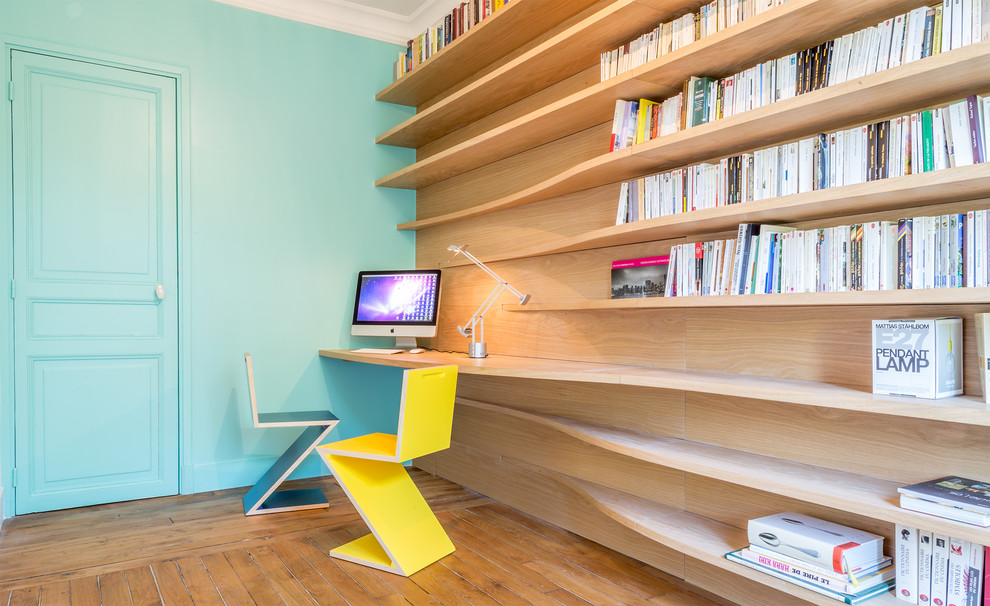 Diseño de despacho actual grande con escritorio empotrado, paredes azules y suelo de madera en tonos medios