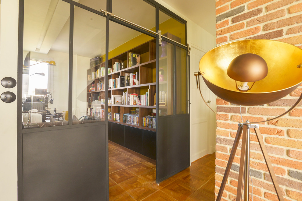Ejemplo de despacho industrial grande con paredes amarillas, escritorio independiente y suelo de madera oscura