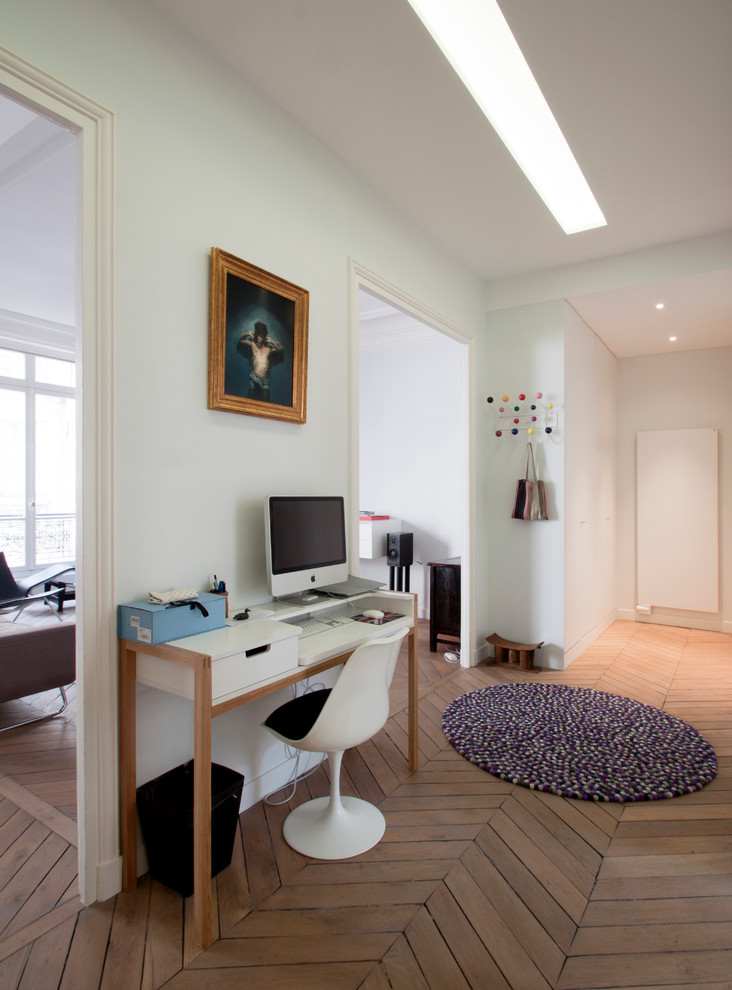 Mittelgroßes Modernes Arbeitszimmer mit Arbeitsplatz, weißer Wandfarbe, braunem Holzboden und freistehendem Schreibtisch in Paris