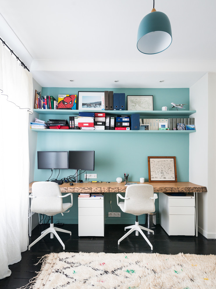 Ejemplo de despacho actual de tamaño medio con suelo de madera pintada, escritorio independiente, suelo negro y paredes blancas