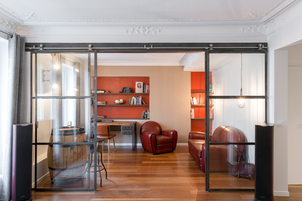 Mittelgroßes Industrial Arbeitszimmer ohne Kamin mit Arbeitsplatz, oranger Wandfarbe, braunem Holzboden und freistehendem Schreibtisch in Paris