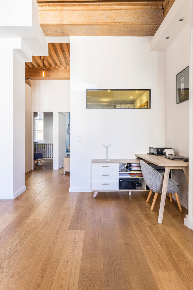 Imagen de despacho escandinavo pequeño sin chimenea con paredes blancas, suelo de contrachapado, escritorio independiente y suelo beige