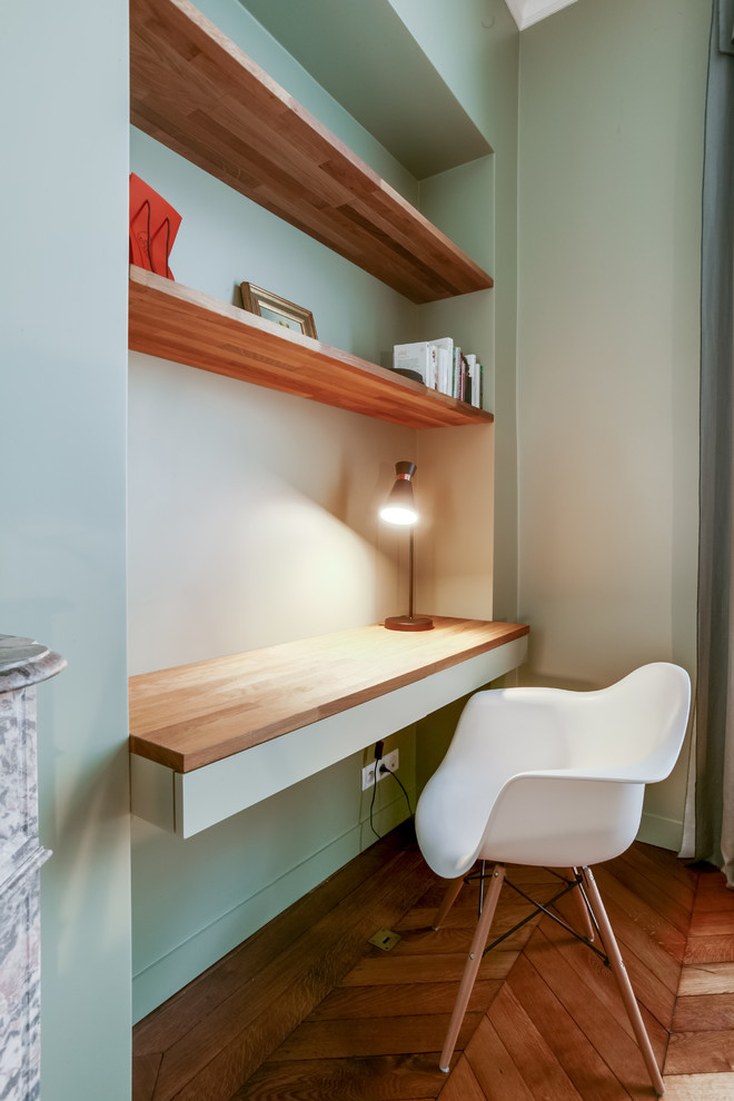 Imagen de despacho minimalista grande con paredes verdes, suelo de madera en tonos medios, todas las chimeneas, marco de chimenea de piedra y suelo marrón
