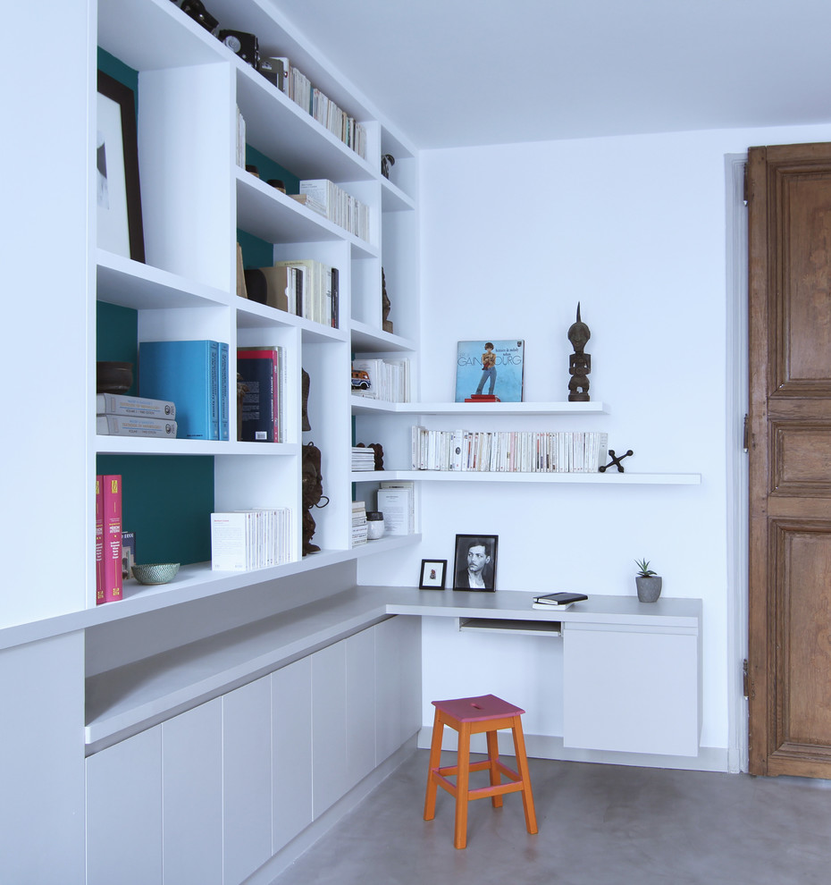 Imagen de despacho actual sin chimenea con paredes blancas, suelo de cemento y escritorio empotrado