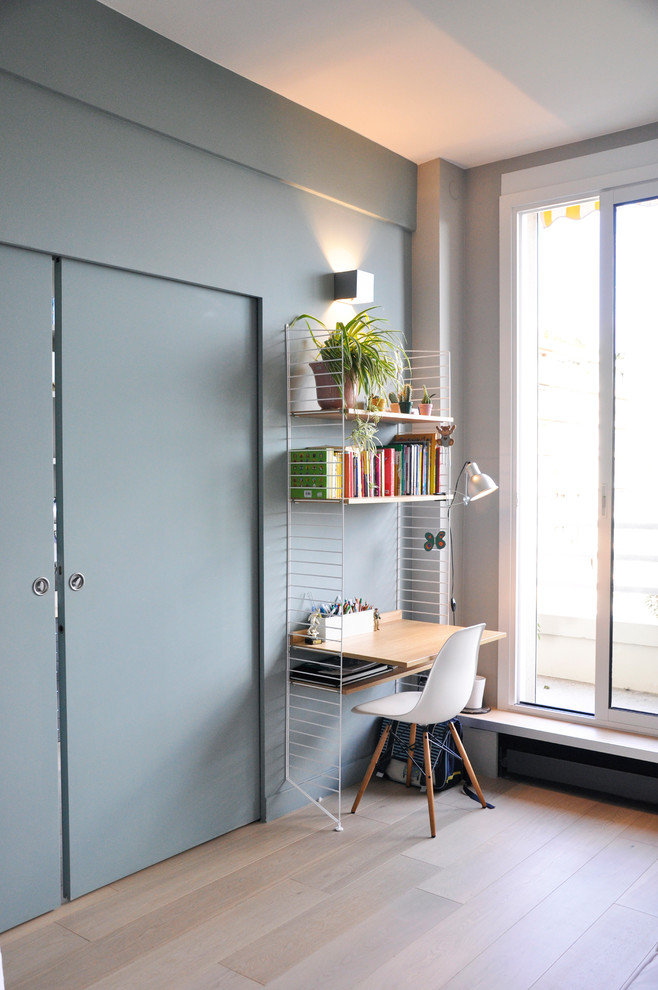 Kleines Modernes Arbeitszimmer mit Arbeitsplatz, blauer Wandfarbe, hellem Holzboden und freistehendem Schreibtisch in Paris