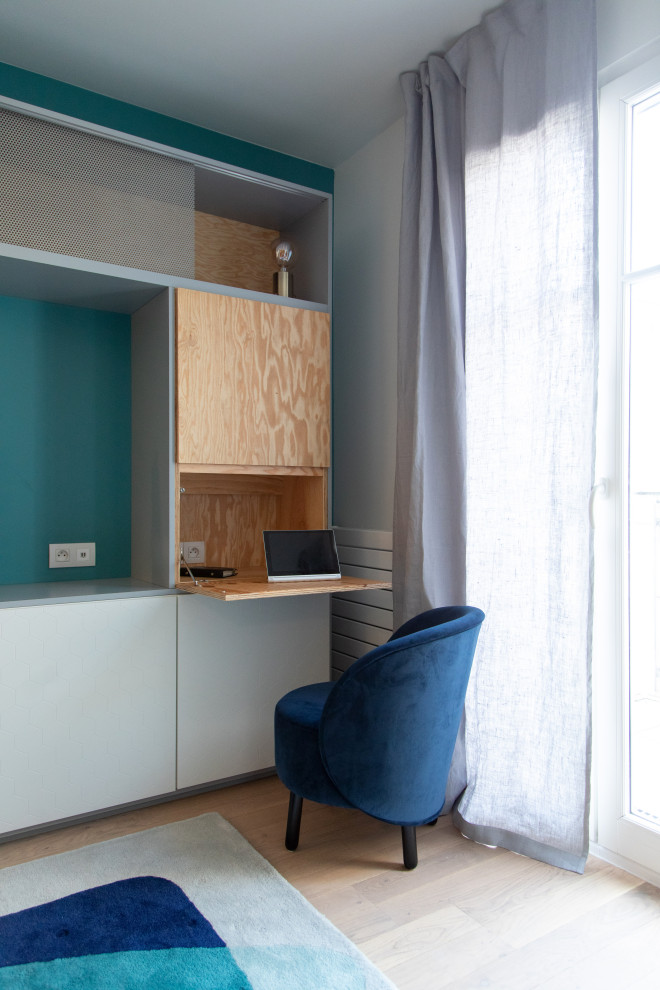 Cette photo montre un bureau moderne de taille moyenne avec un mur bleu, parquet clair, aucune cheminée et un bureau intégré.