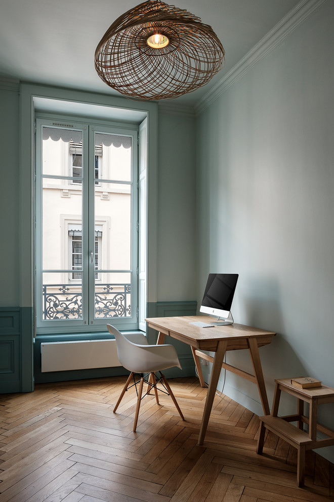 Modernes Arbeitszimmer mit Arbeitsplatz, grüner Wandfarbe, braunem Holzboden, freistehendem Schreibtisch und braunem Boden in Lyon