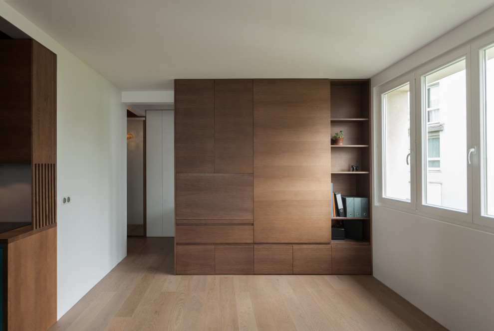 Kleines Modernes Arbeitszimmer ohne Kamin mit Arbeitsplatz, weißer Wandfarbe, hellem Holzboden, Einbau-Schreibtisch und Holzwänden in Paris