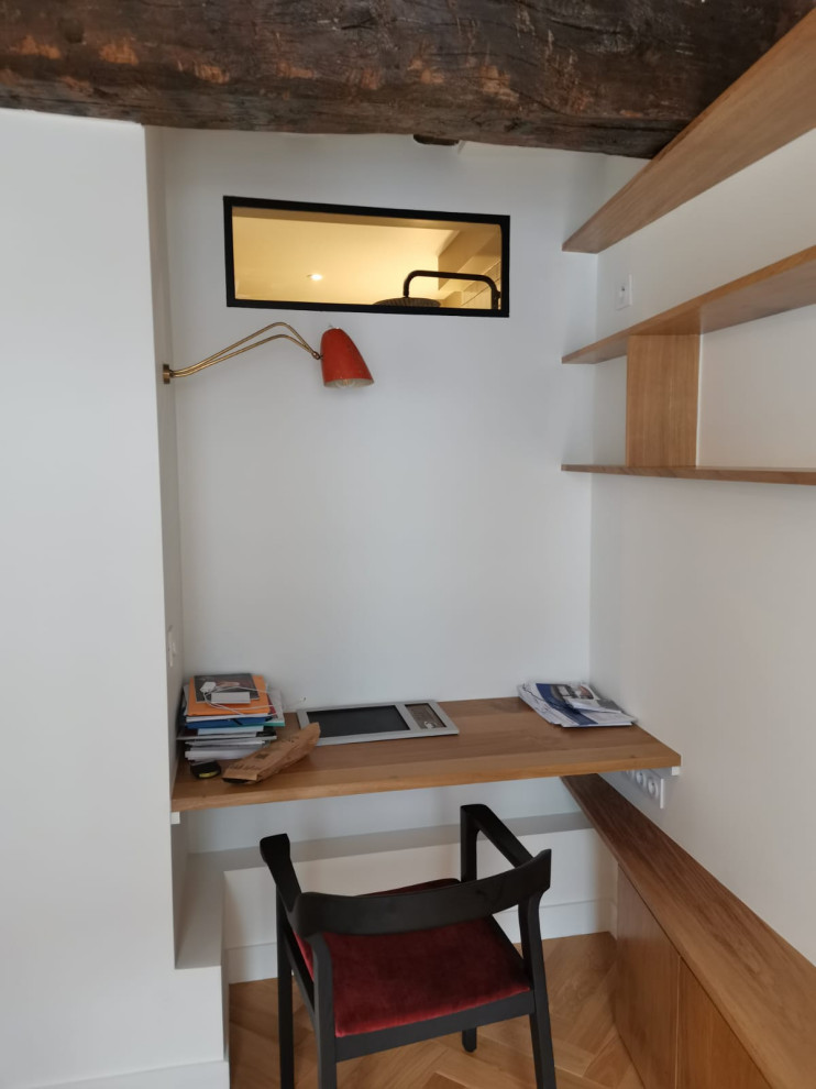 На фото: маленький домашняя библиотека в стиле модернизм с белыми стенами, паркетным полом среднего тона, встроенным рабочим столом, коричневым полом и балками на потолке для на участке и в саду