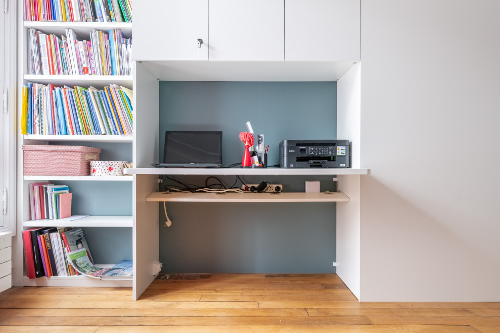 Cette photo montre un bureau tendance de taille moyenne avec parquet clair, un mur bleu, aucune cheminée, un bureau intégré et un sol marron.