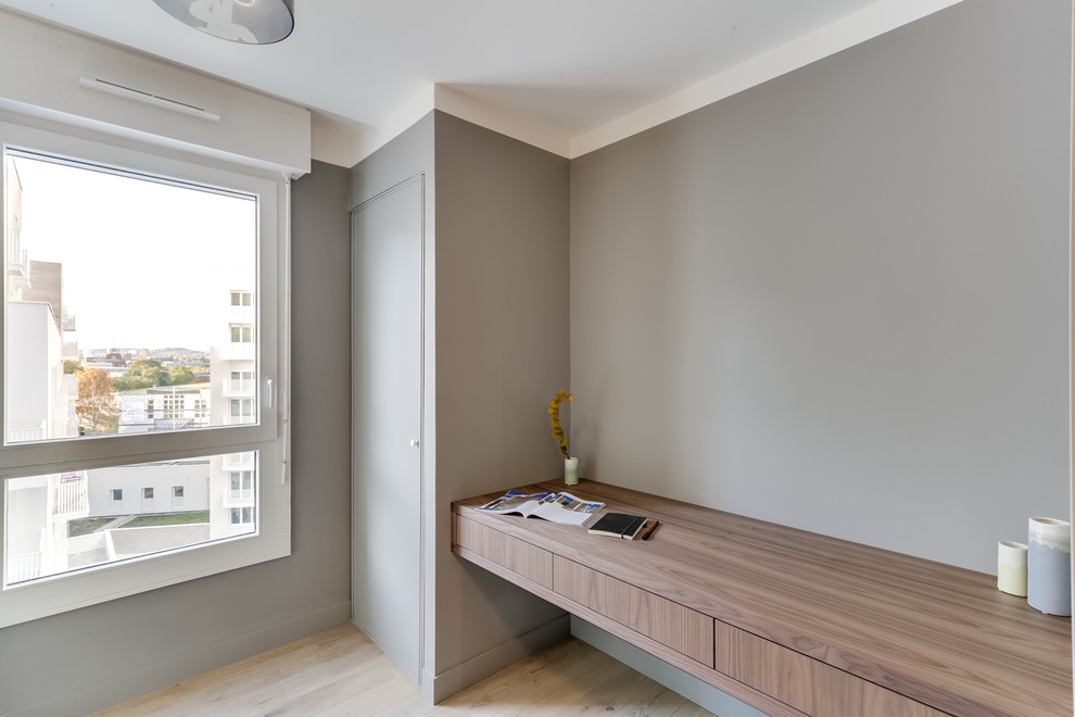Foto de despacho actual con paredes grises y suelo de madera clara