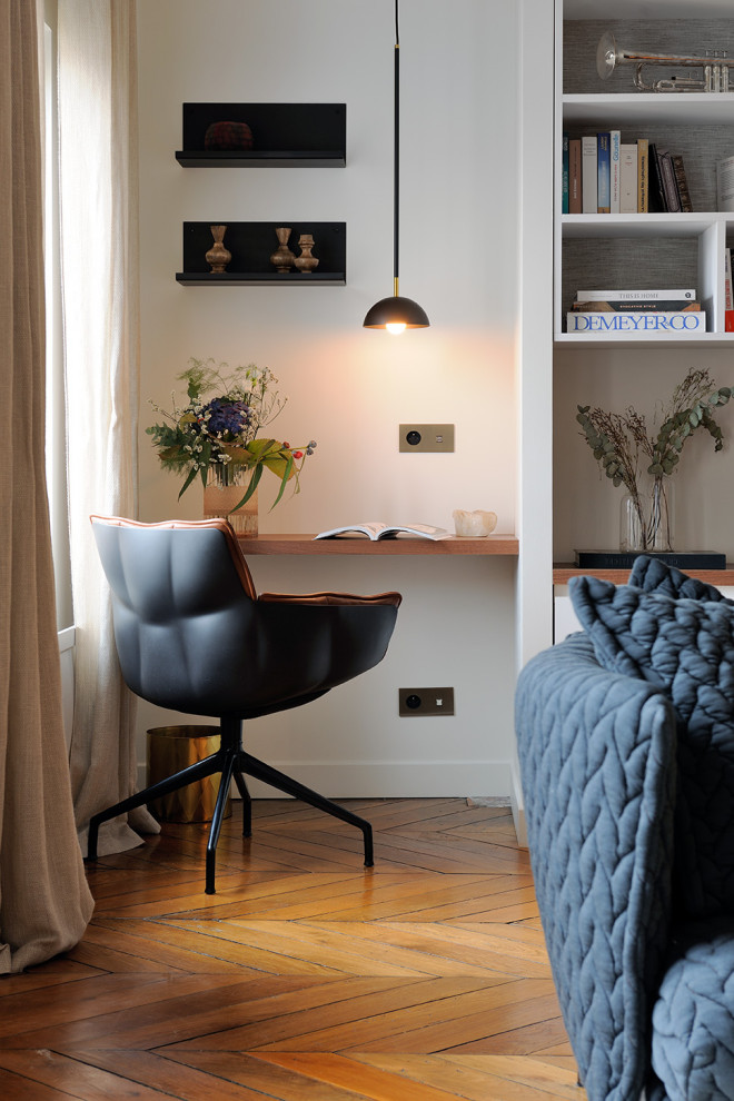 Modernes Arbeitszimmer mit weißer Wandfarbe, braunem Holzboden, Einbau-Schreibtisch und braunem Boden in Lyon