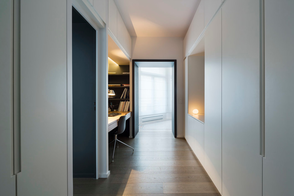 Mittelgroßes Modernes Arbeitszimmer mit Arbeitsplatz, grauer Wandfarbe, hellem Holzboden und Einbau-Schreibtisch in Paris