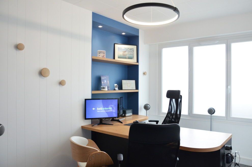 Modelo de despacho actual de tamaño medio con paredes blancas, moqueta, escritorio empotrado, suelo gris y machihembrado