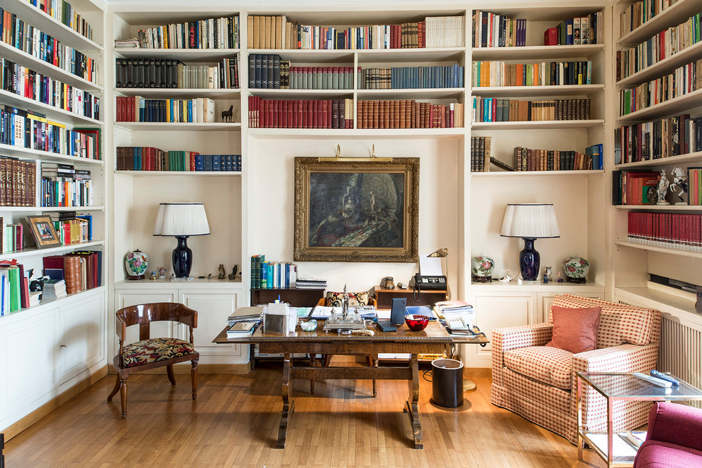 Ispirazione per uno studio tradizionale con libreria, pareti bianche, pavimento in legno massello medio, scrivania autoportante e pavimento marrone
