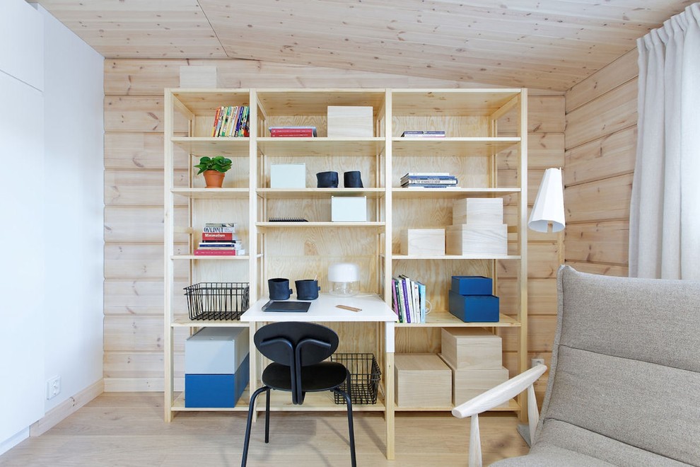 Foto på ett mellanstort skandinaviskt hemmabibliotek, med beige väggar, ljust trägolv och ett fristående skrivbord