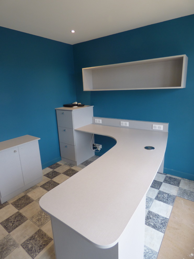 Foto på ett stort funkis arbetsrum, med ett bibliotek, blå väggar, laminatgolv, ett fristående skrivbord och flerfärgat golv
