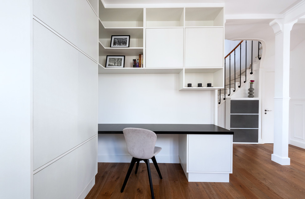 Idée de décoration pour un bureau design de taille moyenne avec un mur blanc, parquet foncé, aucune cheminée, un bureau intégré et un sol marron.