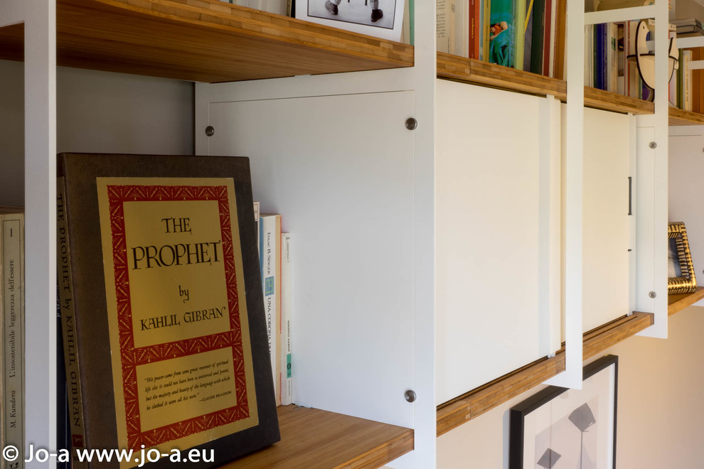 Ejemplo de despacho actual sin chimenea con biblioteca, paredes beige, suelo laminado y escritorio empotrado