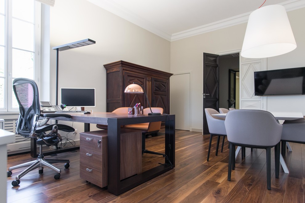 Cette image montre un grand bureau design avec un mur beige et un sol en bois brun.