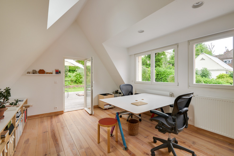 Mid-sized danish freestanding desk light wood floor and brown floor study room photo in Paris with white walls and no fireplace