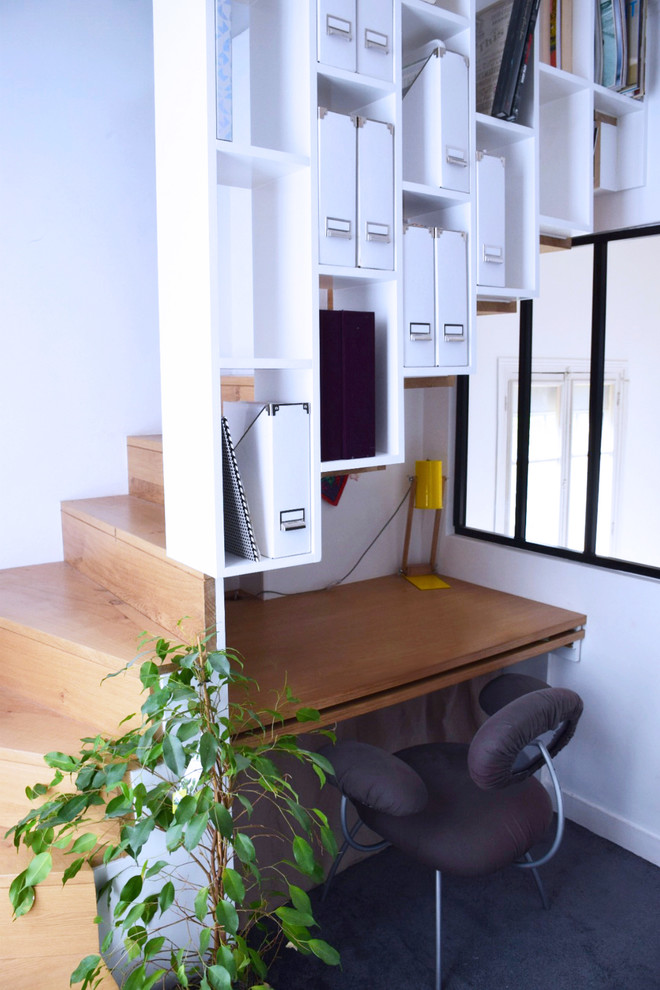 Modelo de despacho moderno pequeño sin chimenea con paredes blancas, moqueta, escritorio empotrado y suelo gris