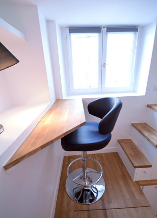 Cette image montre un petit bureau design avec un bureau intégré, un mur blanc et un sol en bois brun.
