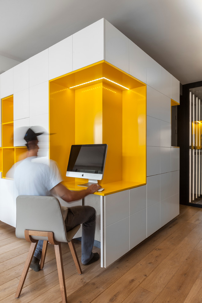 Idée de décoration pour un bureau design de taille moyenne avec un mur jaune, parquet clair, aucune cheminée, un bureau intégré et un sol marron.