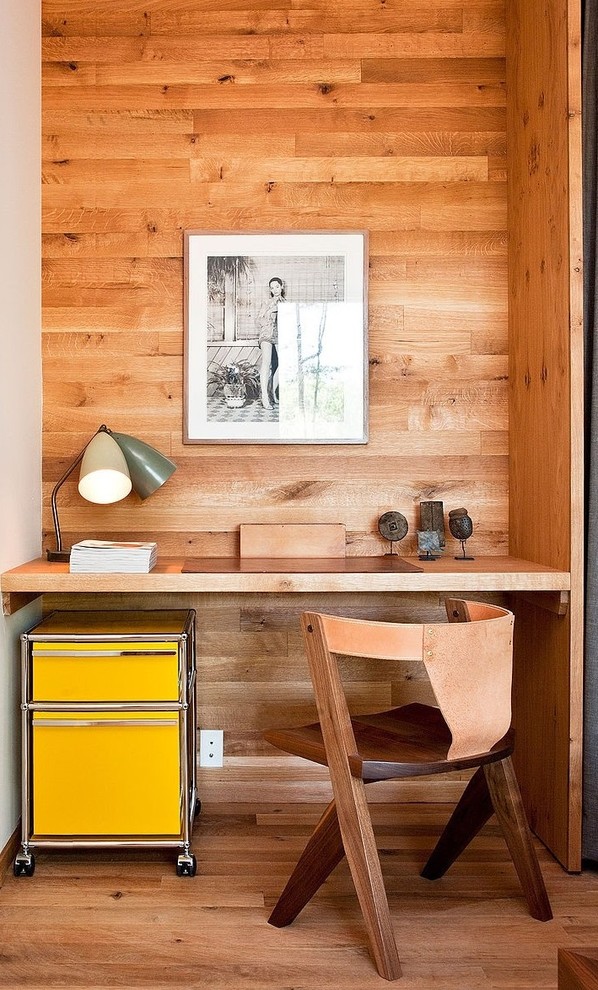 Cette image montre un petit bureau minimaliste avec un sol en bois brun et un bureau intégré.