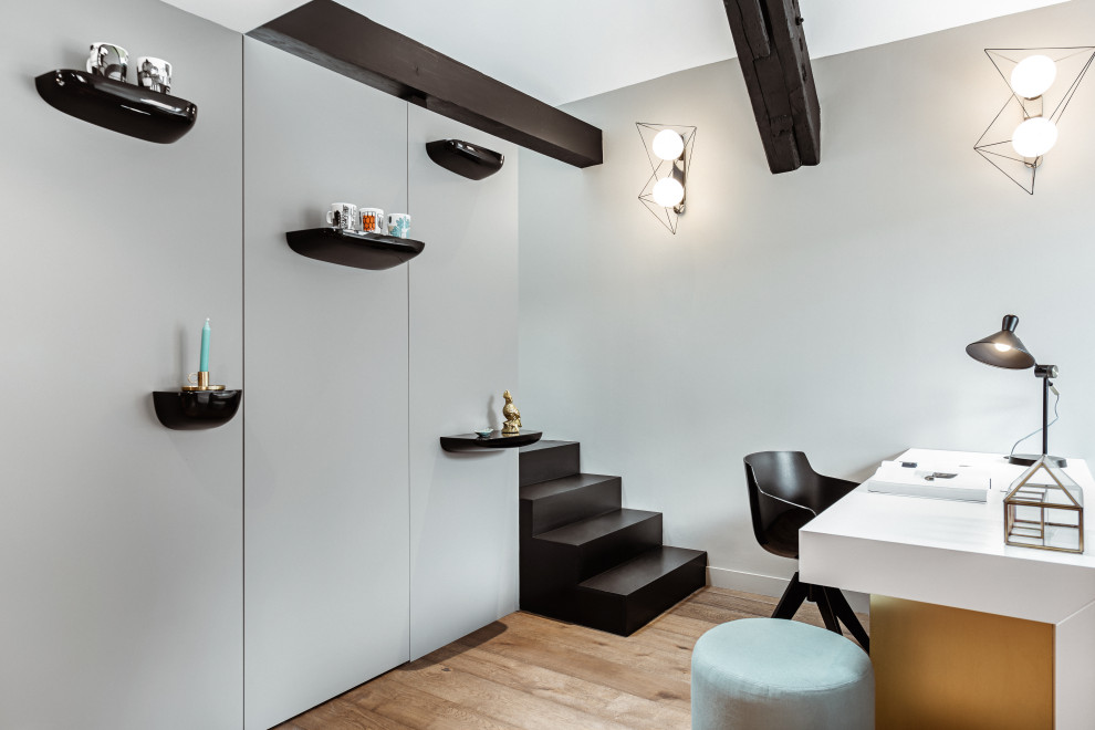 Diseño de despacho nórdico con paredes grises, suelo de madera en tonos medios, escritorio independiente y suelo marrón