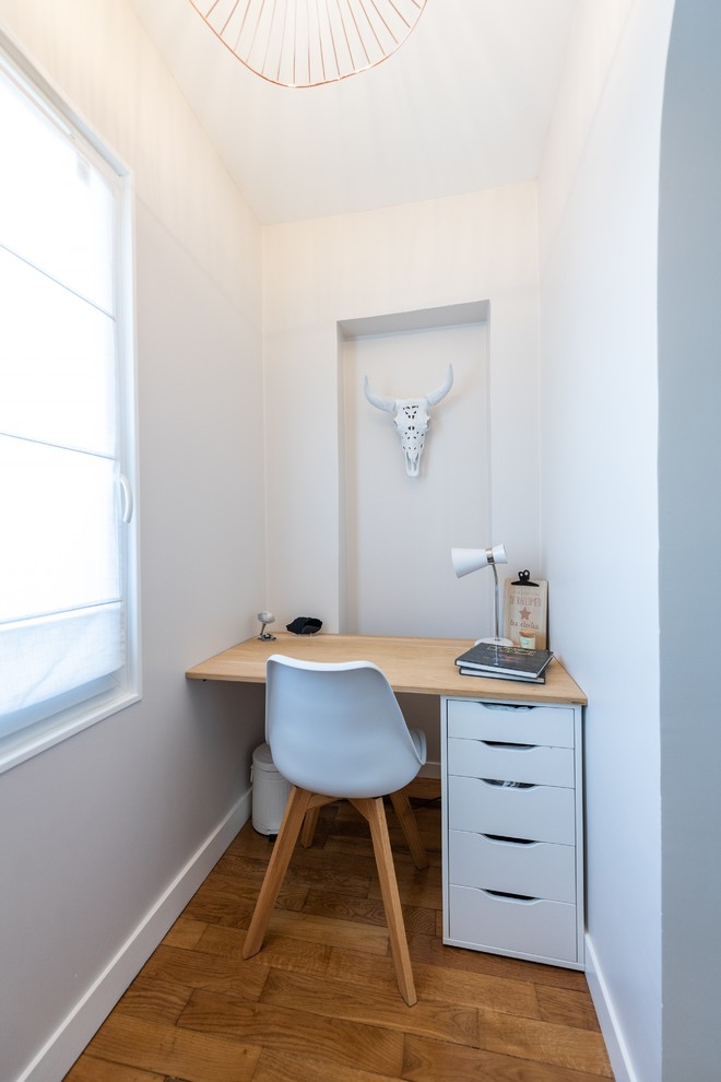 Foto de despacho escandinavo con paredes blancas, suelo de madera en tonos medios, escritorio empotrado y suelo marrón