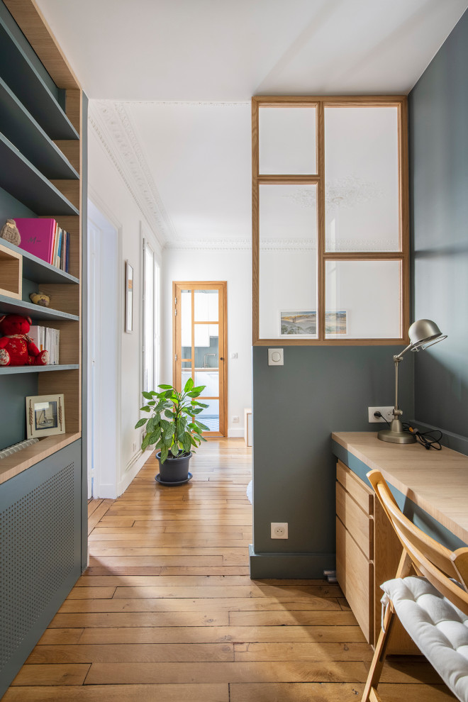 Idee per un piccolo studio nordico con libreria, pareti blu, pavimento in legno massello medio, nessun camino, scrivania incassata e pavimento beige