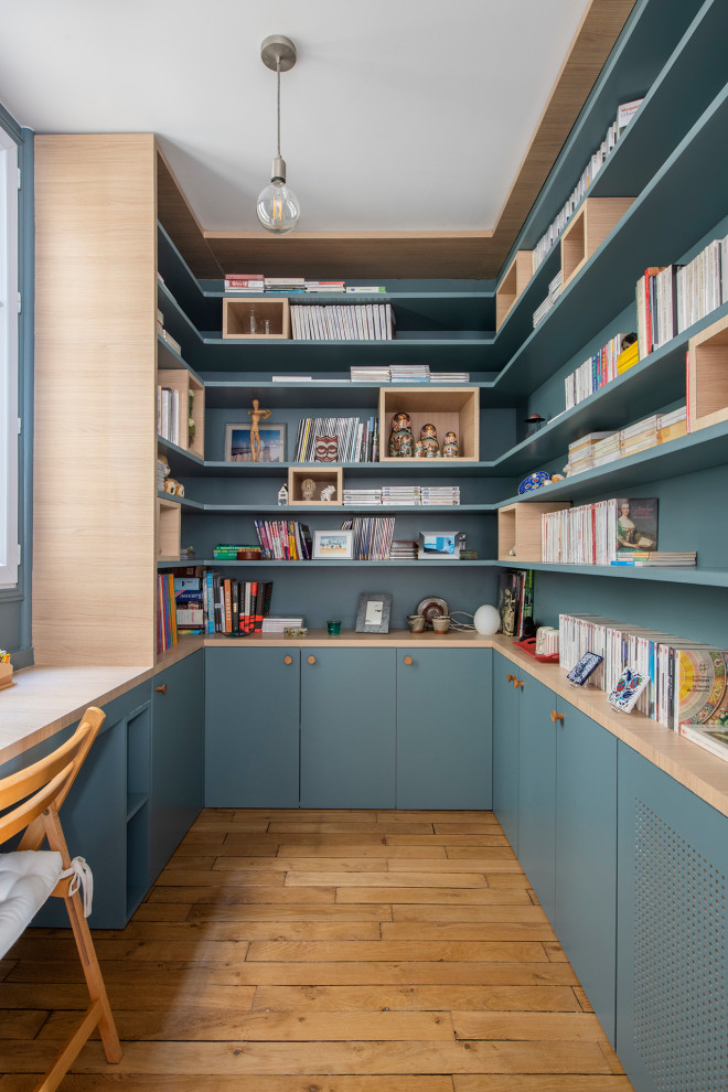 パリにあるお手頃価格の小さな北欧スタイルのおしゃれなホームオフィス・書斎 (ライブラリー、青い壁、無垢フローリング、暖炉なし、造り付け机、ベージュの床) の写真