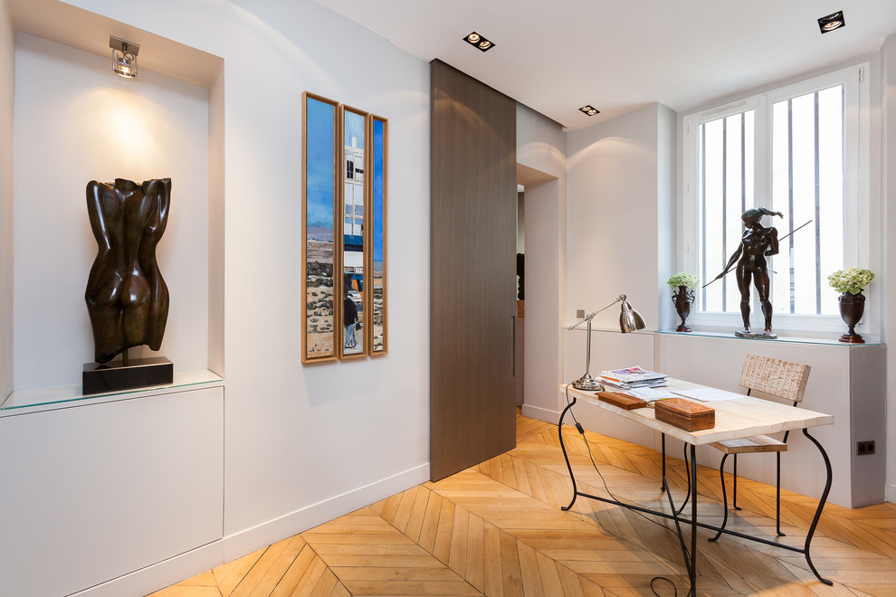 Modernes Arbeitszimmer mit Arbeitsplatz, weißer Wandfarbe, hellem Holzboden und freistehendem Schreibtisch in Paris