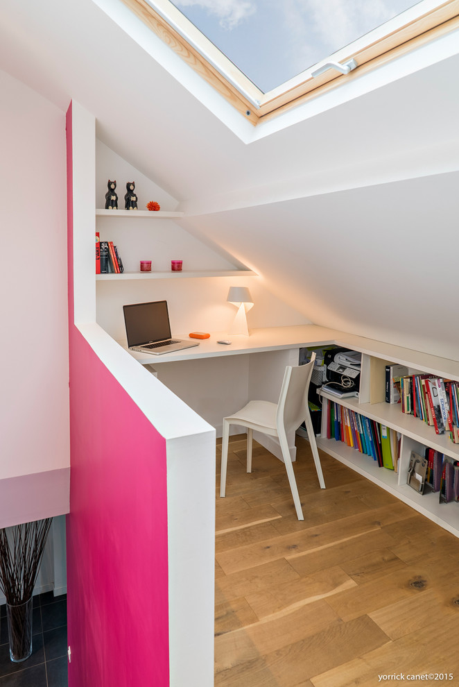 Cette image montre un petit bureau design avec un mur blanc, un sol en bois brun et un bureau intégré.