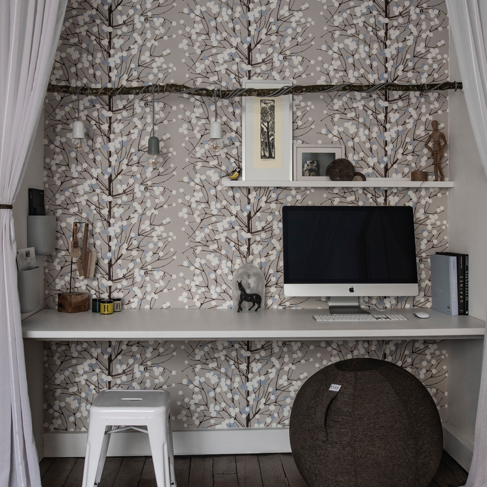 Cette image montre un petit bureau nordique avec un mur beige, un sol en bois brun, un bureau intégré et un sol marron.