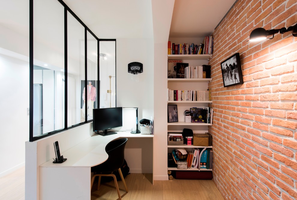 Kleines Industrial Arbeitszimmer mit weißer Wandfarbe, braunem Holzboden, Einbau-Schreibtisch und braunem Boden in Paris