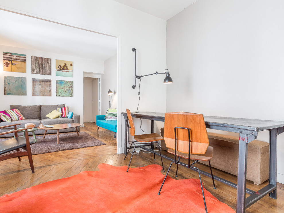 Mittelgroßes Modernes Arbeitszimmer ohne Kamin mit weißer Wandfarbe, braunem Holzboden und freistehendem Schreibtisch in Paris