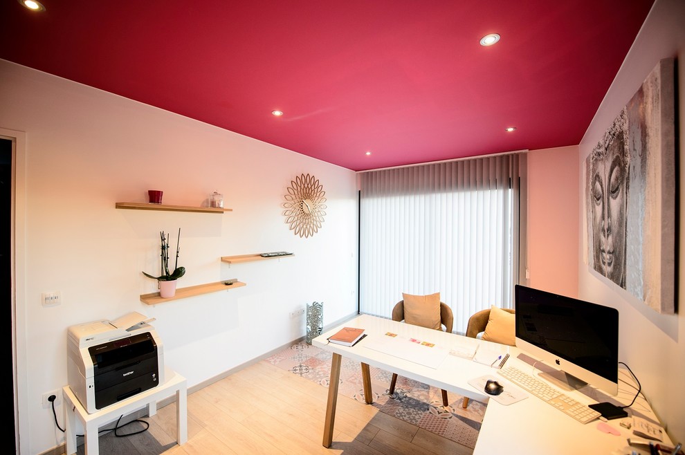 Ejemplo de despacho asiático de tamaño medio con paredes rojas, suelo laminado, escritorio independiente y suelo beige