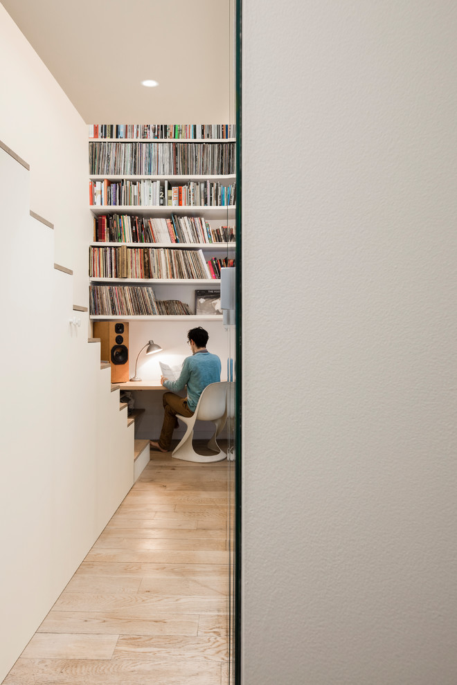Exemple d'un bureau tendance avec une bibliothèque ou un coin lecture, un mur blanc, parquet clair, aucune cheminée, un bureau intégré et un sol beige.