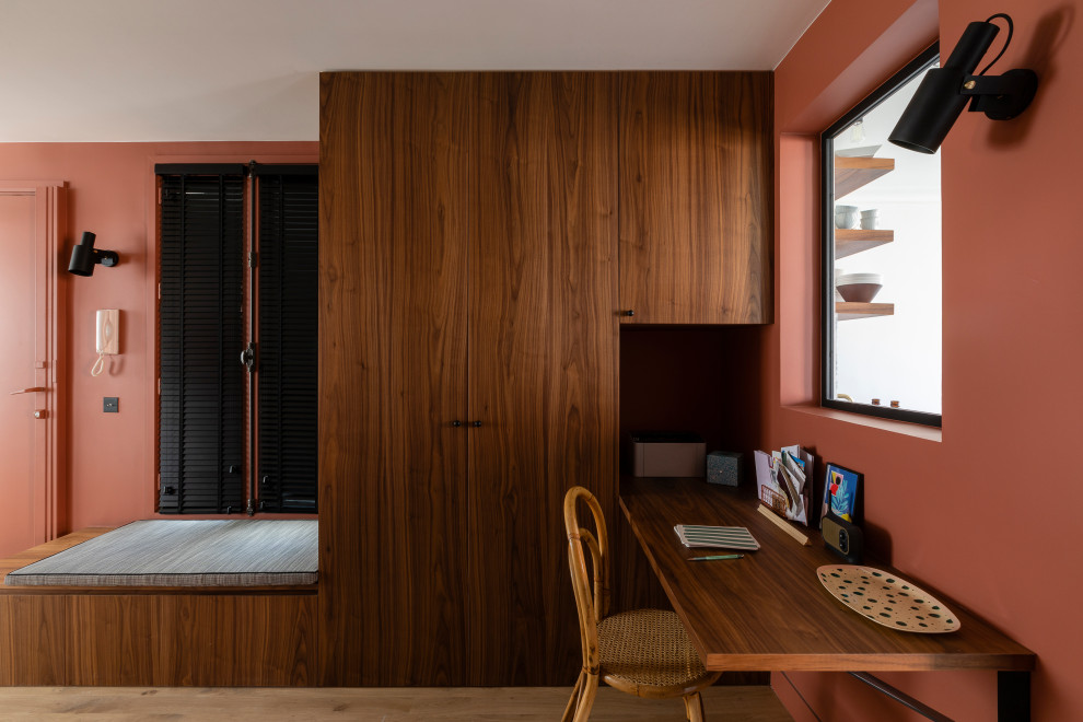 Inspiration för mellanstora moderna hemmabibliotek, med röda väggar, ljust trägolv och ett inbyggt skrivbord