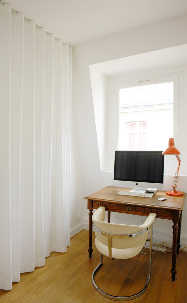 Imagen de despacho actual pequeño sin chimenea con paredes blancas, suelo de madera clara, escritorio independiente y suelo marrón