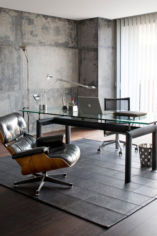 Modelo de despacho actual de tamaño medio con suelo de madera oscura, escritorio independiente y paredes grises