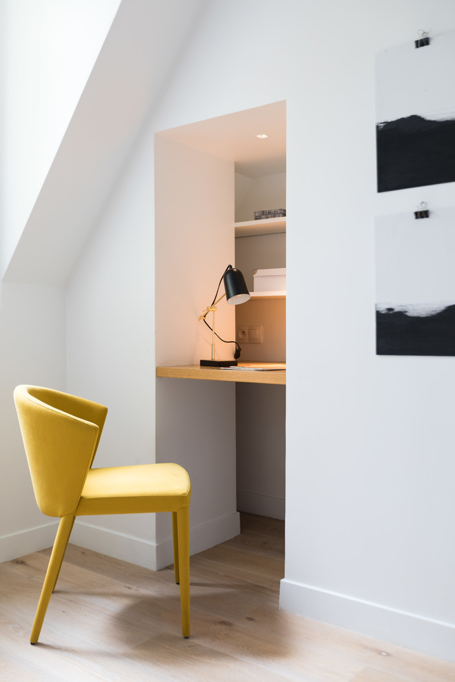 Modernes Arbeitszimmer mit weißer Wandfarbe, hellem Holzboden, Einbau-Schreibtisch und beigem Boden in Paris