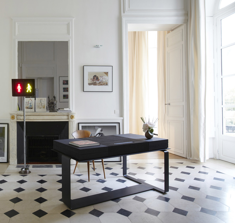 パリにあるラグジュアリーな広いコンテンポラリースタイルのおしゃれな書斎 (標準型暖炉、石材の暖炉まわり、自立型机、白い壁、マルチカラーの床) の写真