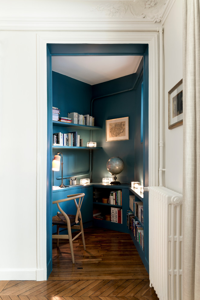 パリにある高級な小さなコンテンポラリースタイルのおしゃれな書斎 (青い壁、無垢フローリング、造り付け机、茶色い床) の写真