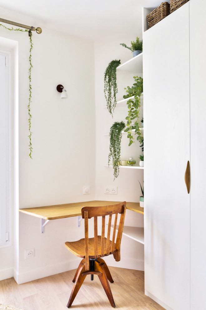 Foto på ett mellanstort minimalistiskt arbetsrum, med vita väggar, ljust trägolv, en spiselkrans i trä och ett inbyggt skrivbord