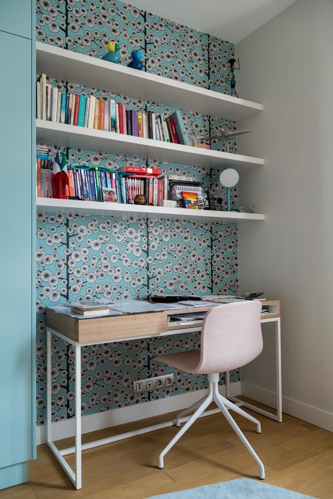 Modelo de despacho contemporáneo de tamaño medio sin chimenea con paredes azules, suelo de madera en tonos medios y escritorio independiente
