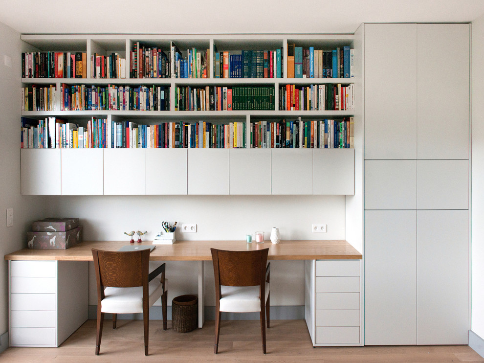 Large scandi study in Paris with white walls, light hardwood flooring and a built-in desk.